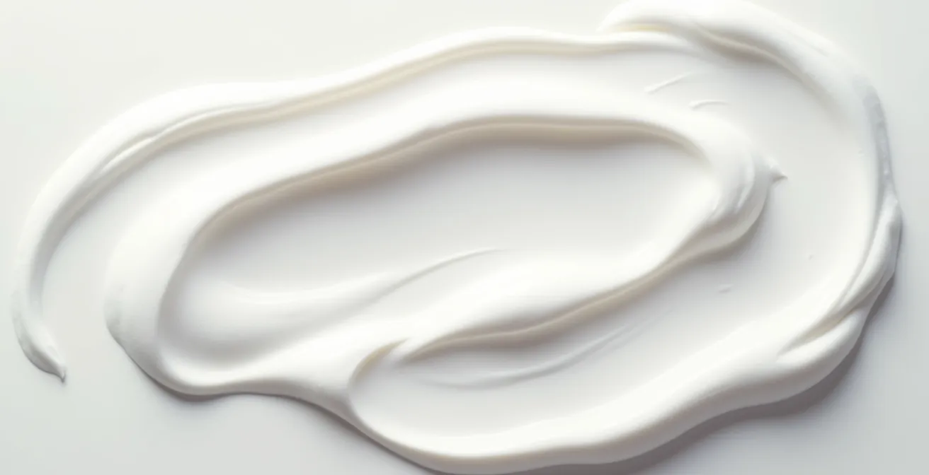 Vue macro d'une texture de crème minérale blanche et épaisse étalée, montrant l'opacité caractéristique de l'oxyde de zinc non-nano.